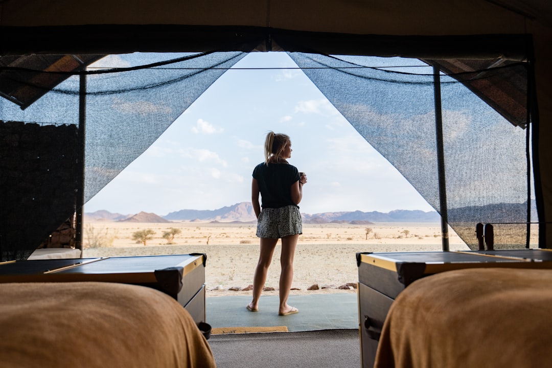 A woman standing in a tent looking out at the desert