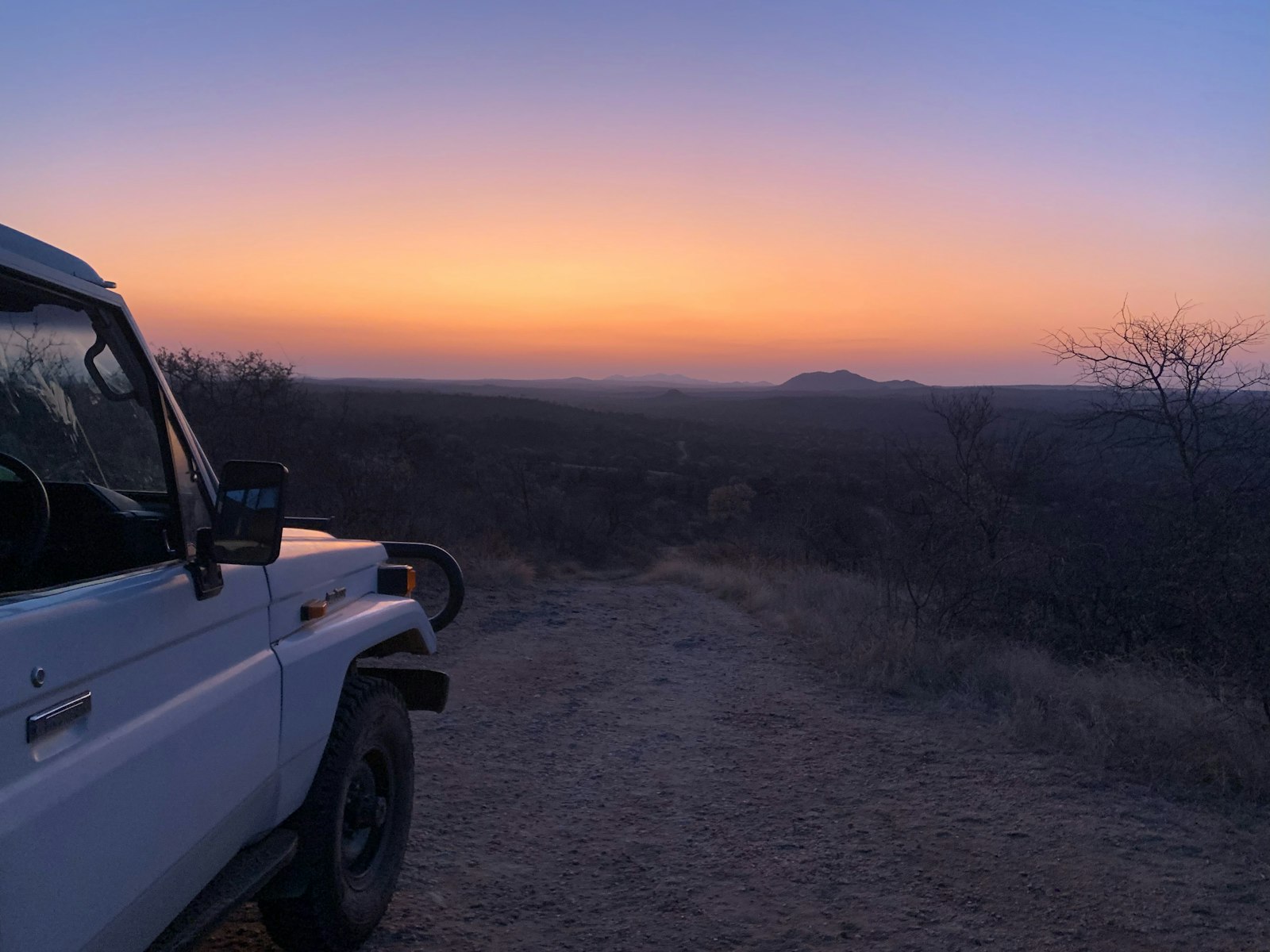 A 4x4 parked on a dirt road in Namibia with open landscape around it