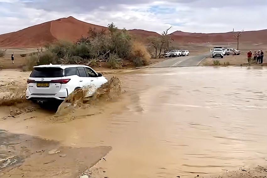 Fahrzeug fährt nach seltenem Regen durch Hochwasser auf der Straße nahe Sossusvlei